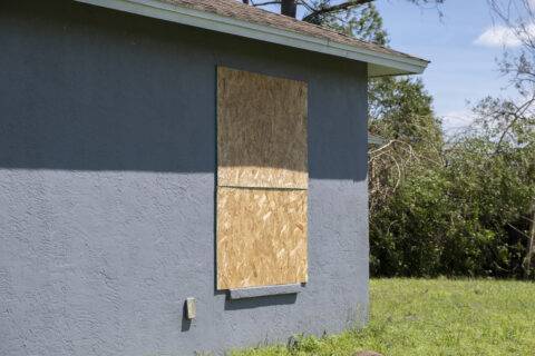 Plywood mounted as storm shutters for hurricane protection of house windows. Protective measures before natural disaster in Florida.