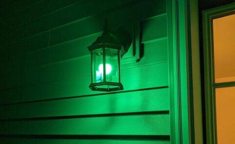 A porch light with a green bulb in it.