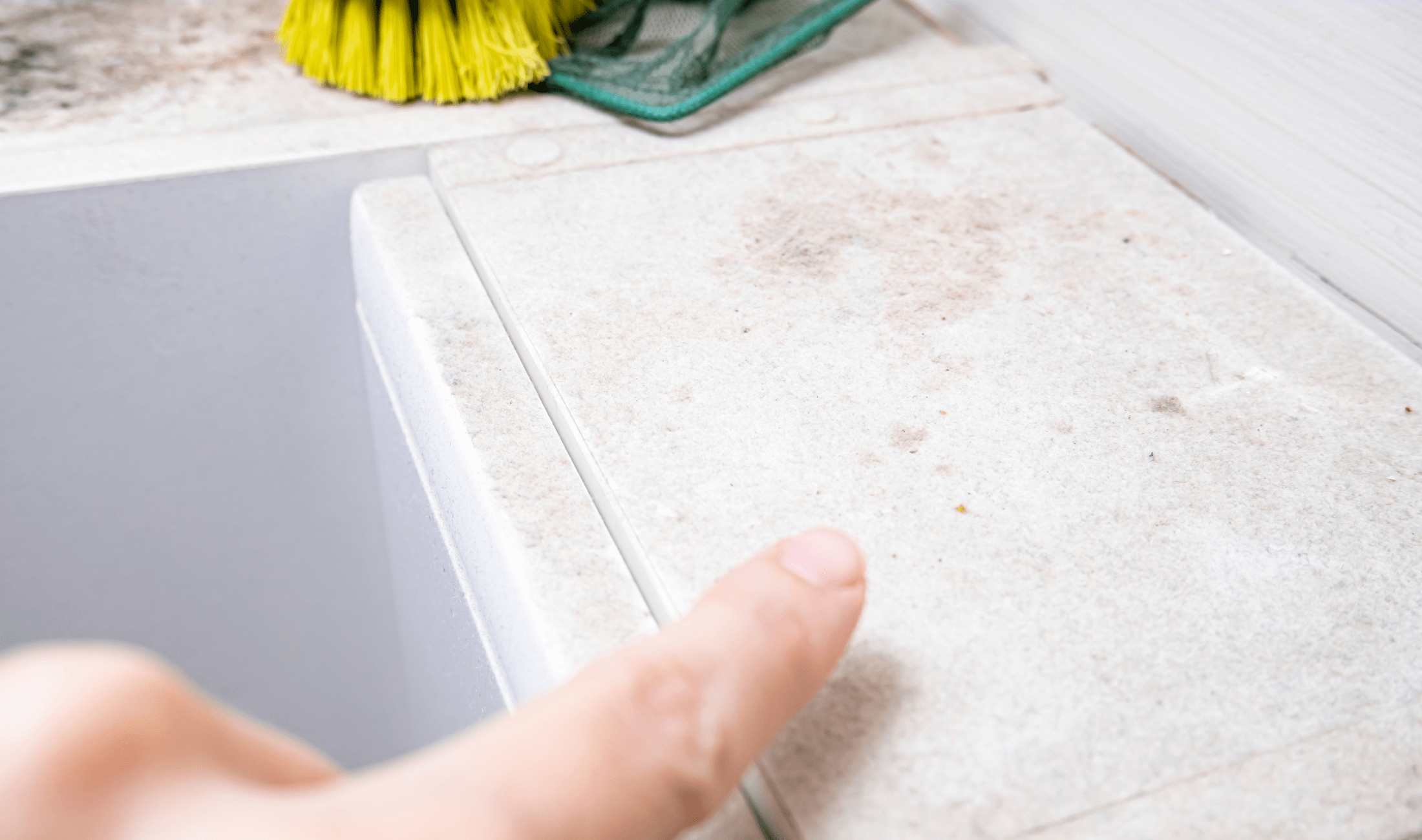 A person pointing at a dusty surface in their home.