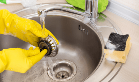 A person cleaning a sink plug.